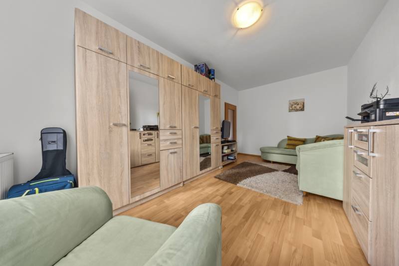 Living room with cabinets, green sofas, and wood-patterned flooring in a 4-room apartment.