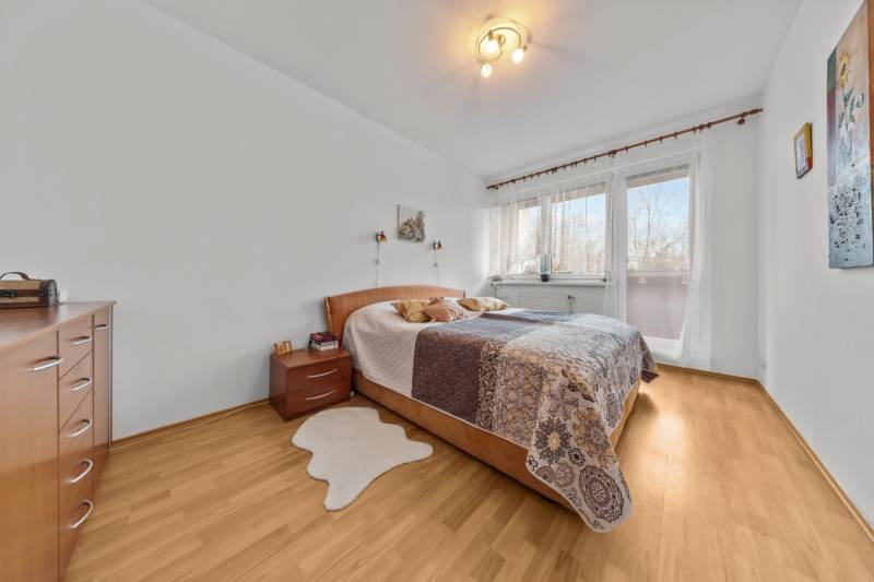 A bedroom with a bed and a wooden decor floor in a 4-room apartment.