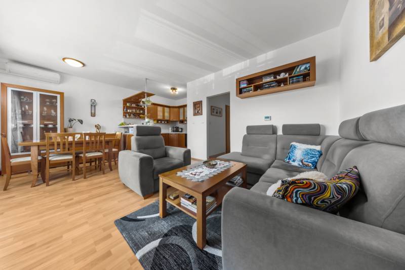 Living room and kitchen with a gray set, wooden furniture, and a floor with a wood decor.
