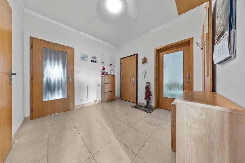 Entrance hall of a 4-room apartment with tiles and wooden doors.