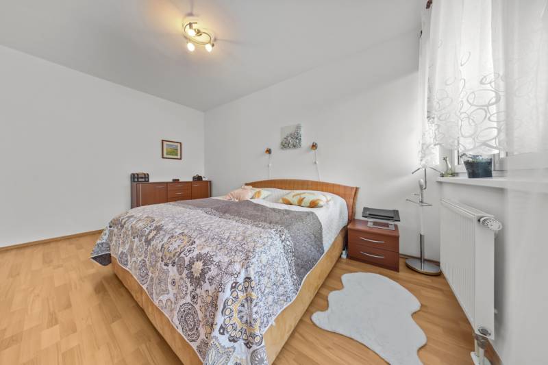 A bedroom in a 4-room apartment with a wood-patterned floor and cozy furnishings.