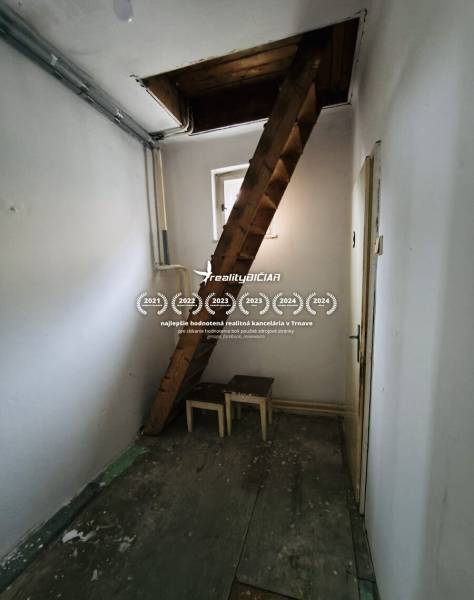 Narrow room with a wooden staircase and a window in a family house.