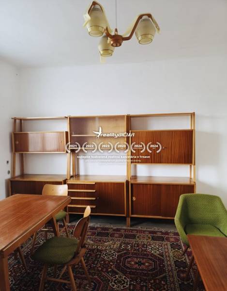 The interior of a family house with carpets, wooden furniture, and a dining table in a medium-sized room.