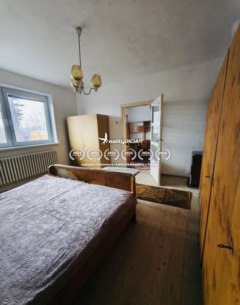 A bedroom in a family house with wooden floor decor, simple furniture, and a chandelier.