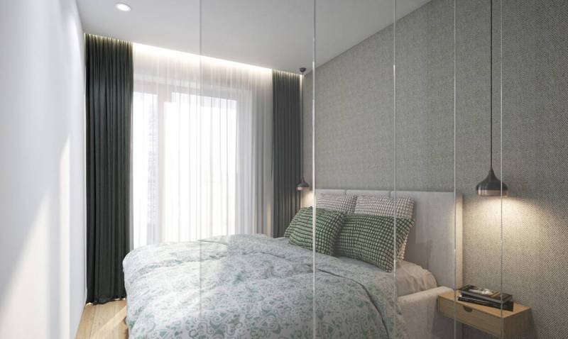 A bedroom with a bed, textured wall, and curtains in a studio apartment.