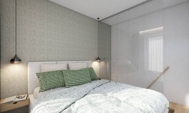 A bedroom with a bed and a built-in wardrobe in a studio apartment with soft lighting.