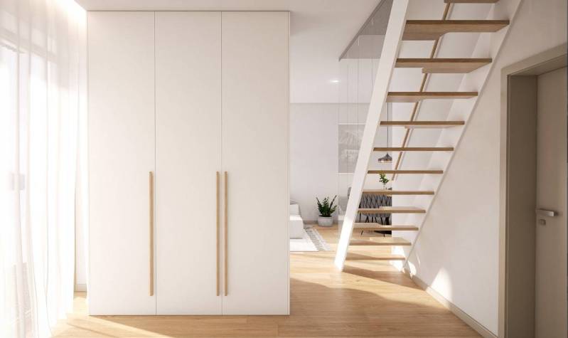 1-room apartment with a staircase, white wardrobe, and wooden decor flooring.