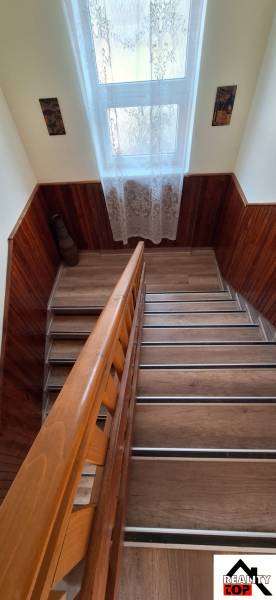 A staircase in a family house with a wooden decor floor and a large window.