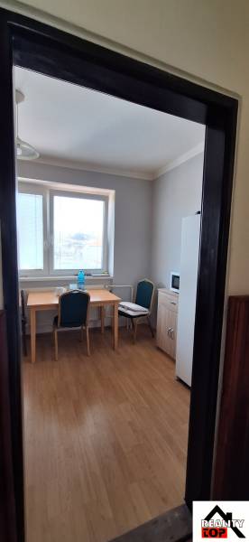Interior of a family house with a window, table, chairs, and a wooden-patterned floor.