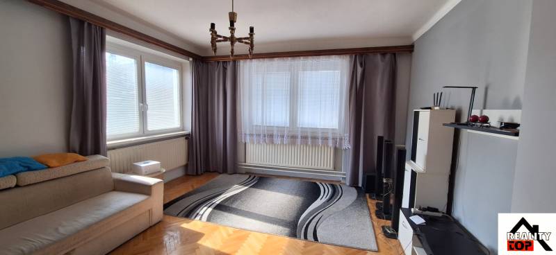 Living room with wood-patterned flooring, a sofa, and gray curtains in a family house.