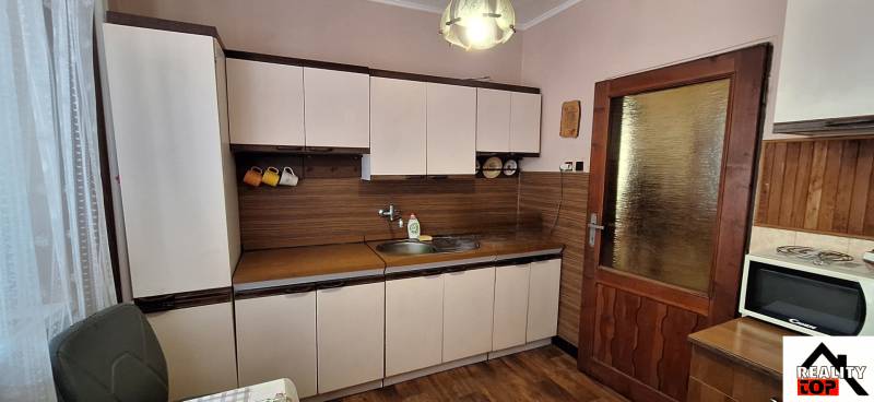 A kitchen with wooden decor and a countertop in a family house, equipped with appliances.
