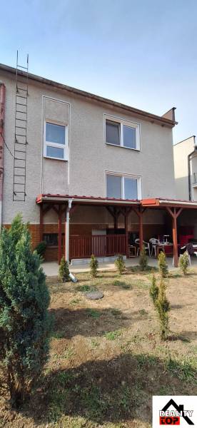 A family house in Gemerský Jablonec with a terrace and a landscaped garden with shrubs.