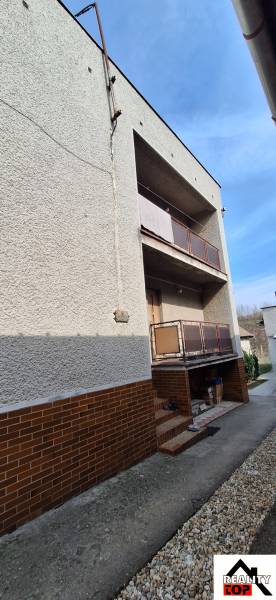 A family house in Gemerský Jablonec with two balconies and a brick cladding.