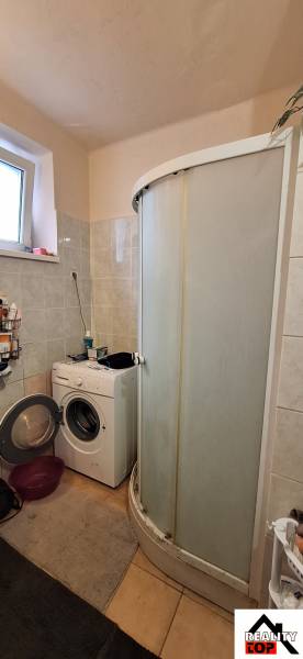 Bathroom in a family house with a shower and a washing machine.