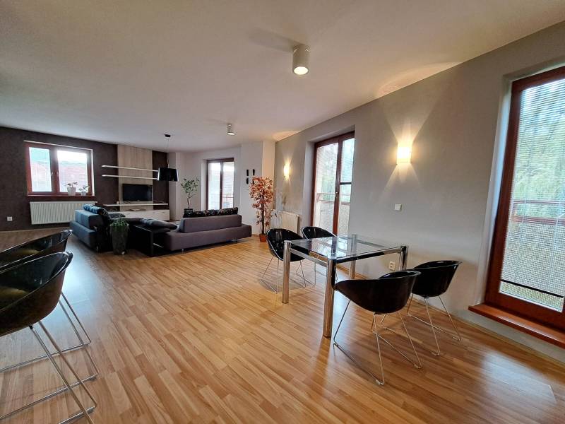 Living room in a two-room apartment with a spacious sofa and a wooden decor floor.