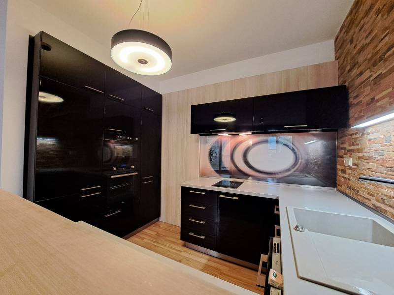 A kitchen in a 2-room apartment with a wood-patterned floor and dark cabinets.