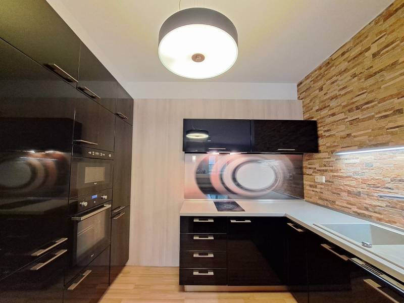 A kitchen in a 2-room apartment with a wooden decor floor and stone cladding.