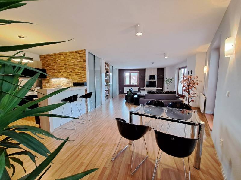 Living room in a two-room apartment with a wooden decor floor and a dining table.