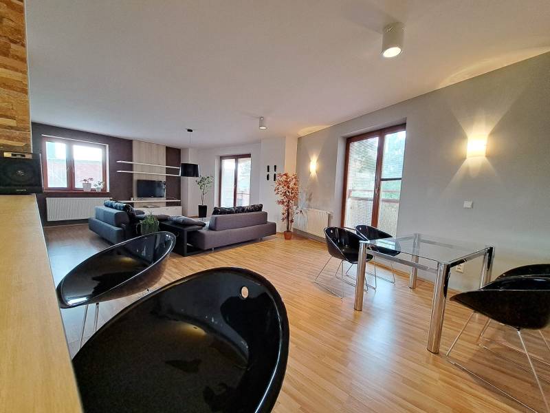 Spacious living area in a 2-room apartment with wood-patterned flooring.