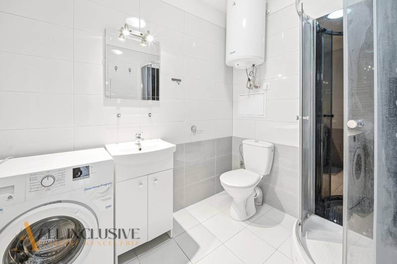 The bathroom in the 3-room apartment includes a washing machine, a shower corner, and white sanitary ware.