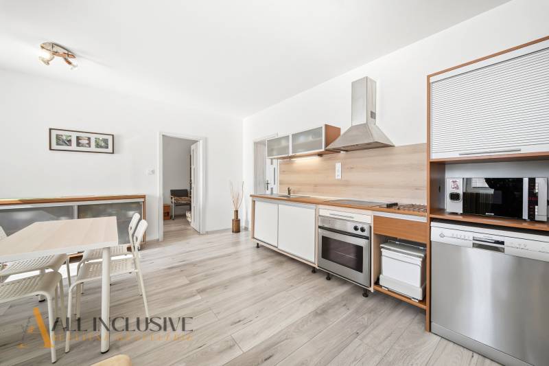 A kitchen in a 3-room apartment with a wooden decor floor and modern equipment.