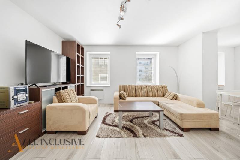 Living room in a three-room apartment with a sofa and a wooden decor floor.