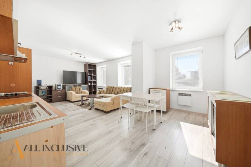 A spacious living room with wood-patterned flooring in a three-room apartment.