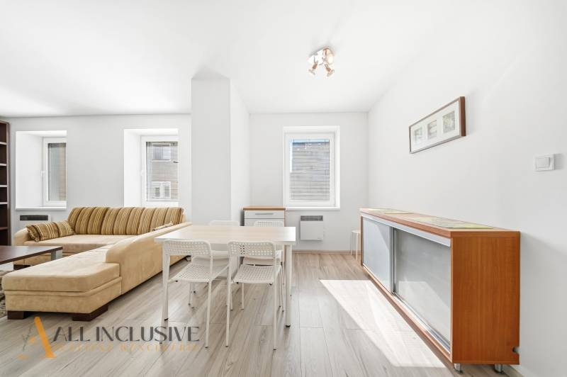 A bright living room in a 3-room apartment with wood-patterned flooring and comfortable seating.