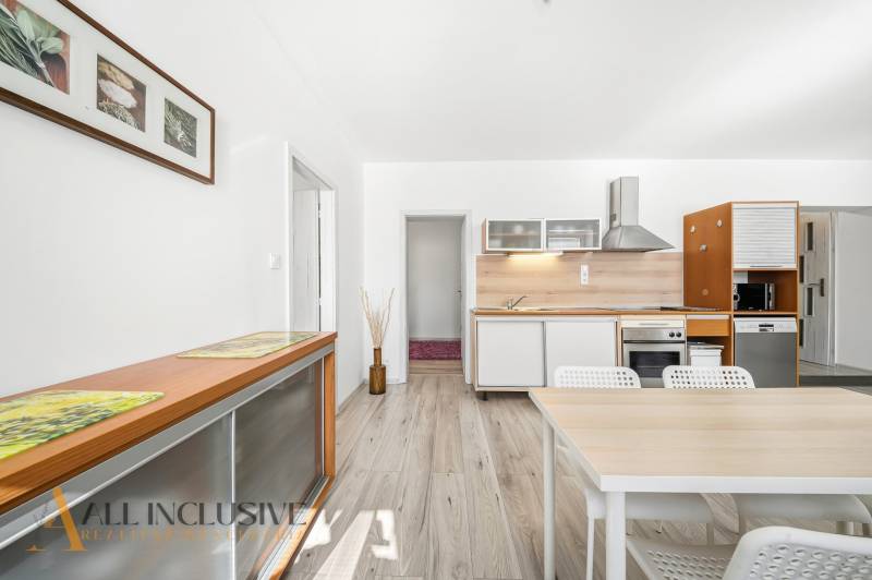 A kitchen in a 3-room apartment with light furniture and a wooden decor floor.