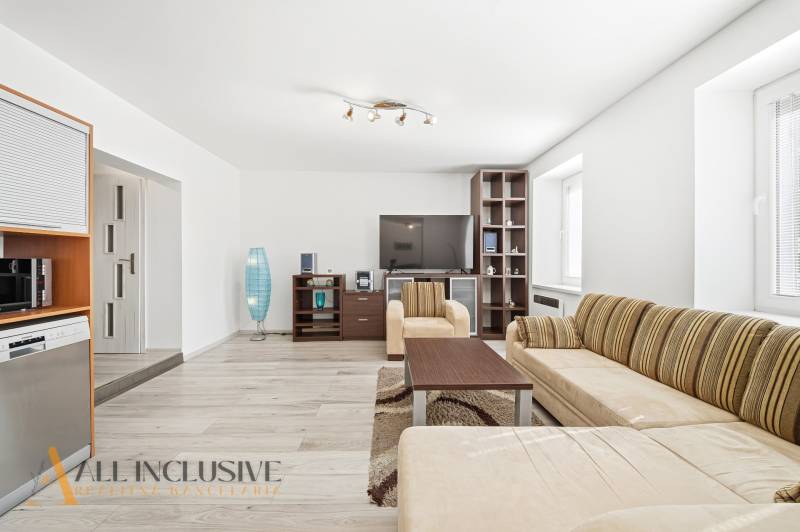 Living room with seating furniture, TV, lamp, and wooden decor flooring in a 3-room apartment.