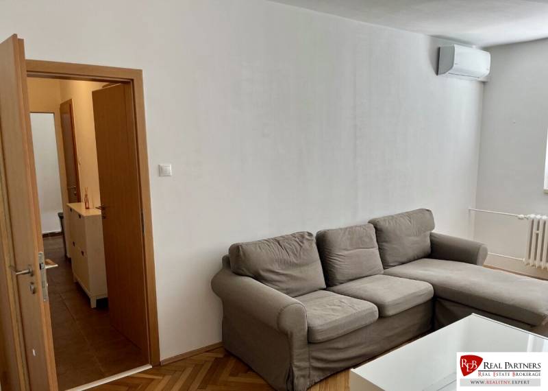 Living room in a two-room apartment with a sofa, wooden floor decor, air conditioning.