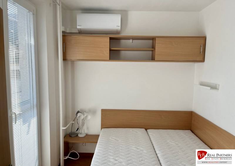 Bedroom in a 2-room apartment with a bed, cabinet, and air conditioning.