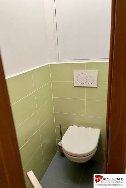A toilet in a 2-room apartment with white and light green tiles.