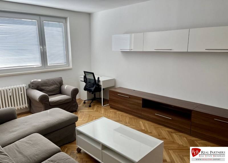 Living room with wood-patterned flooring, sofa, coffee table, and desk.