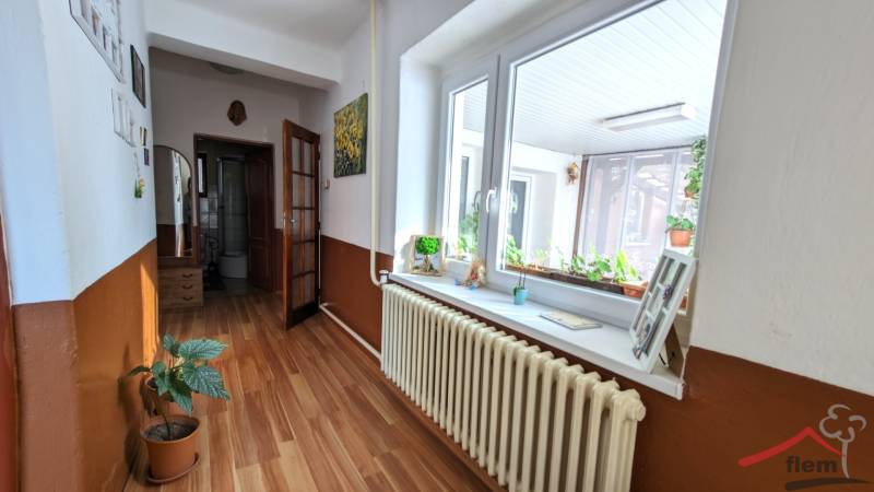 A hallway in a family house with a wooden decor floor and flowers on the windowsill.