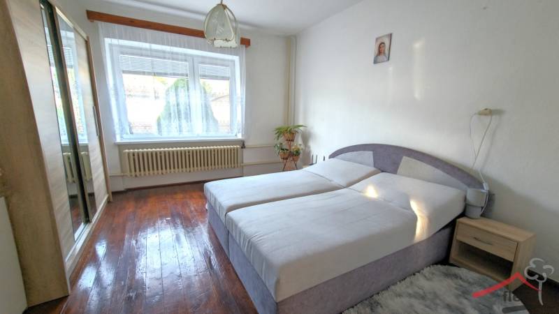 A bedroom in a family house with a wooden decor floor, a bed, and a wardrobe.
