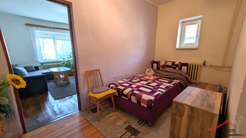 A bedroom in a family house with a bed, a chair, and a wooden decor floor.