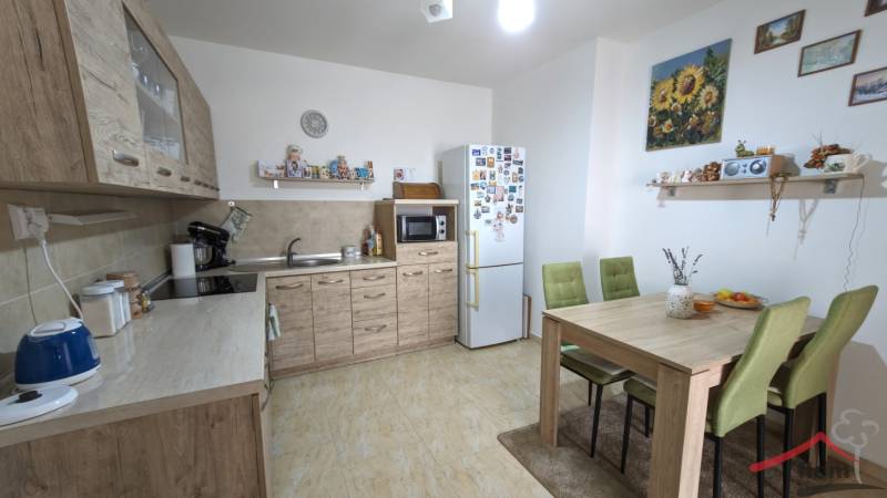 A family house kitchen with wooden decor, a dining table, and green chairs.