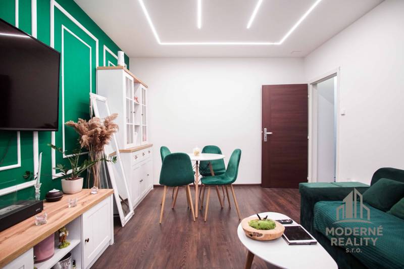 Living room in a 2-room apartment with wooden decor and green accessories.