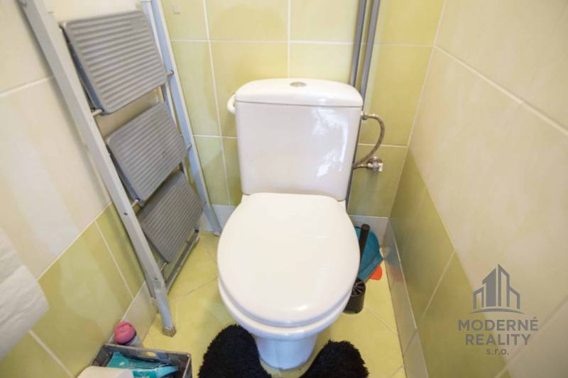 Bathroom toilet with tiles and a ladder dryer in a 2-room apartment.