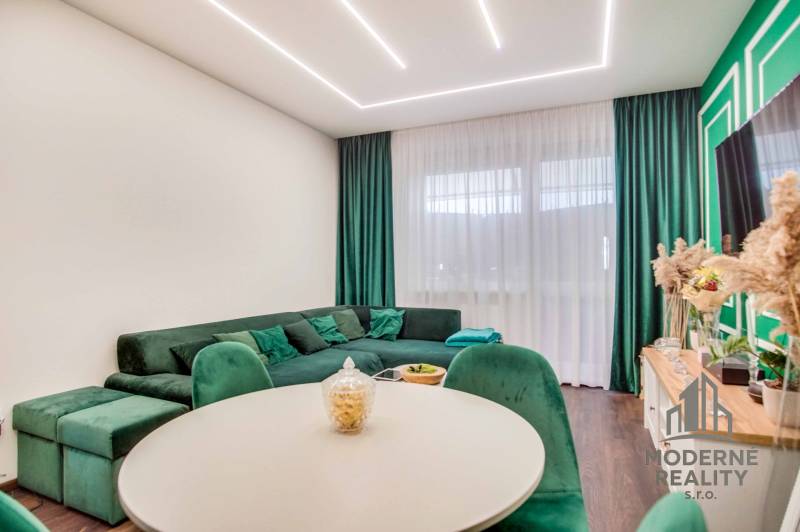 Living room with a comfortable green sofa and a wooden decor floor in a two-room apartment.