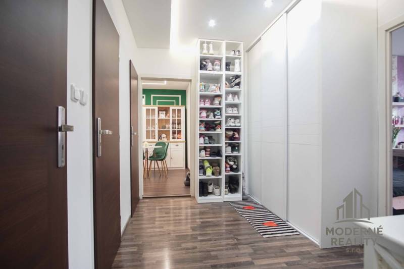A hallway of a 2-room apartment with integrated storage space and a wooden decor floor.