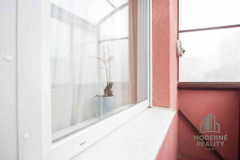 Balcony of a 2-room apartment with a flowerpot and curtains, exterior of Nové Zámky.