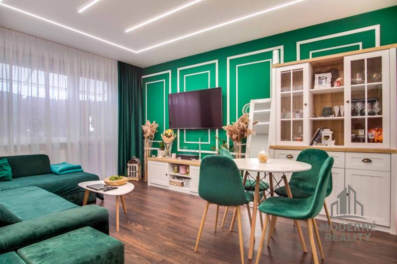 Living room in a two-room apartment with a wooden decor floor and green furniture.