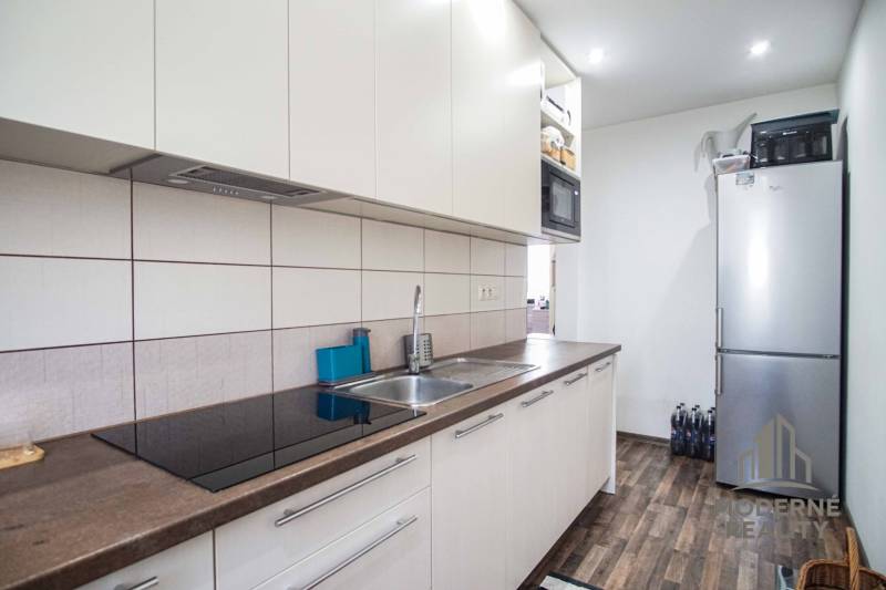 A kitchen in a 2-room apartment with furnishings and a wooden decor floor.