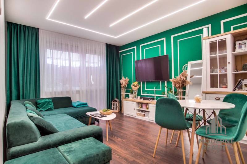 Living room in a two-room apartment with a comfortable sofa and a wooden-patterned floor.