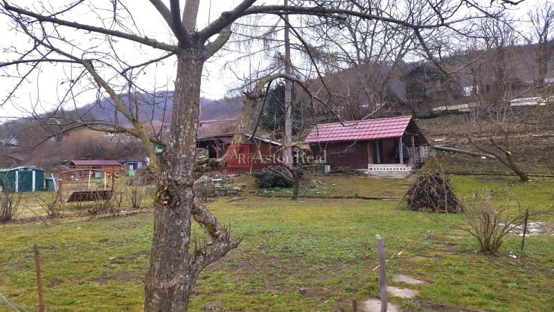 Gardens on Srnkova Street in Banská Bystrica with wooden cottages and trees.