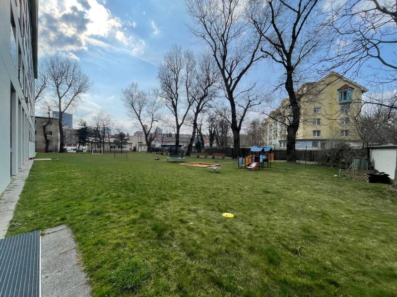 A spacious lawn with trees in Bratislava at Nivy on Košická with a play element.