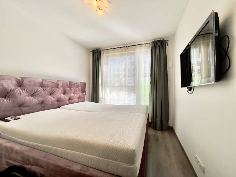 Bedroom with a bed, television, and wooden decor flooring in a 3-room apartment.