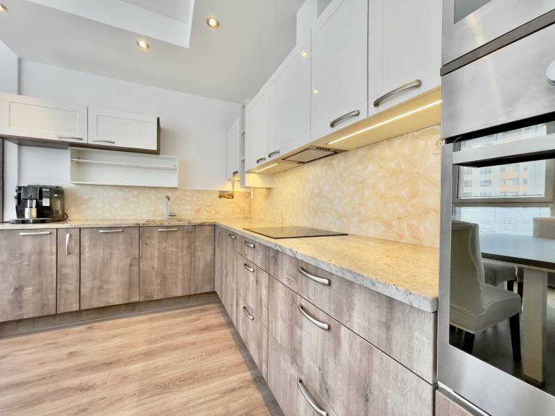 A kitchen in a 3-room apartment with a wood-patterned floor and modern cabinets.